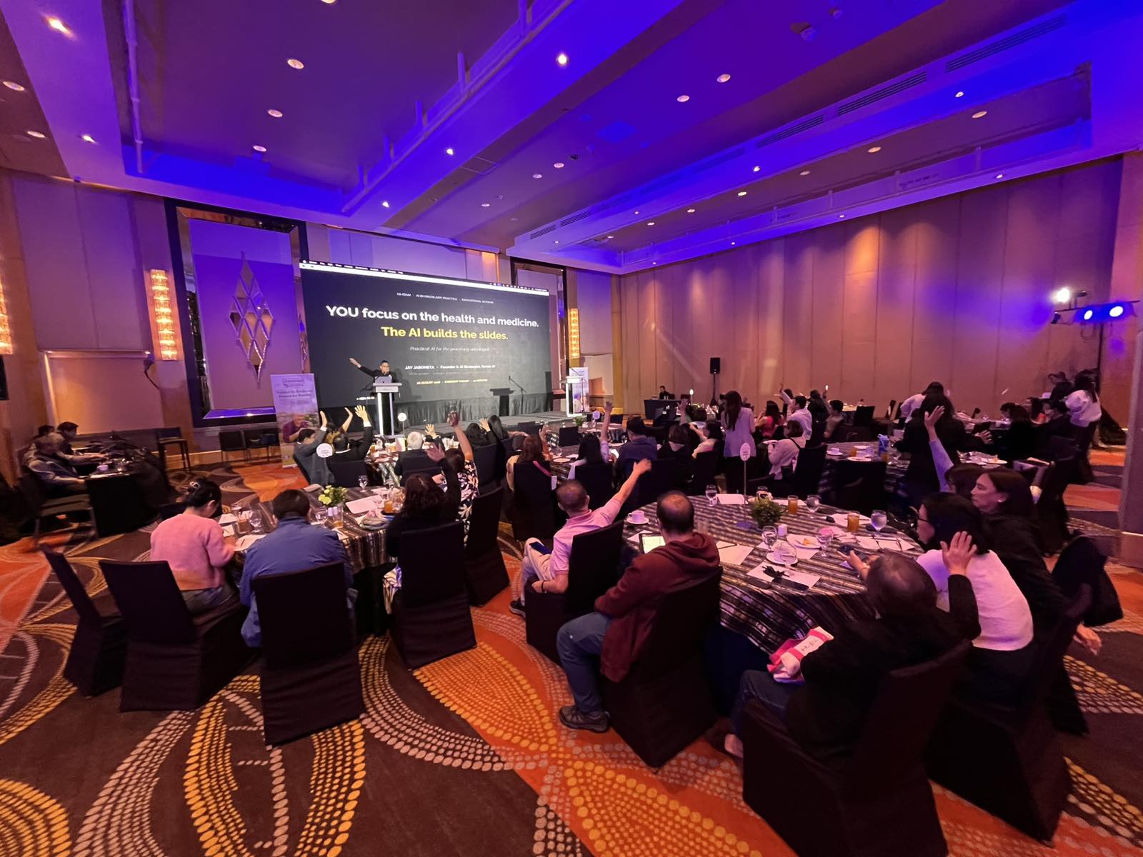 Oncologists raising their hands during Jay Jaboneta's AI keynote at the HI-Eisai HONE Summit