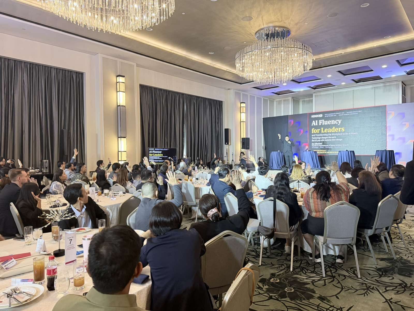 A ballroom of CGI leaders raising their hands during Jay Jaboneta's AI Fluency for Leaders keynote at PGDC Leadership Connect 2026