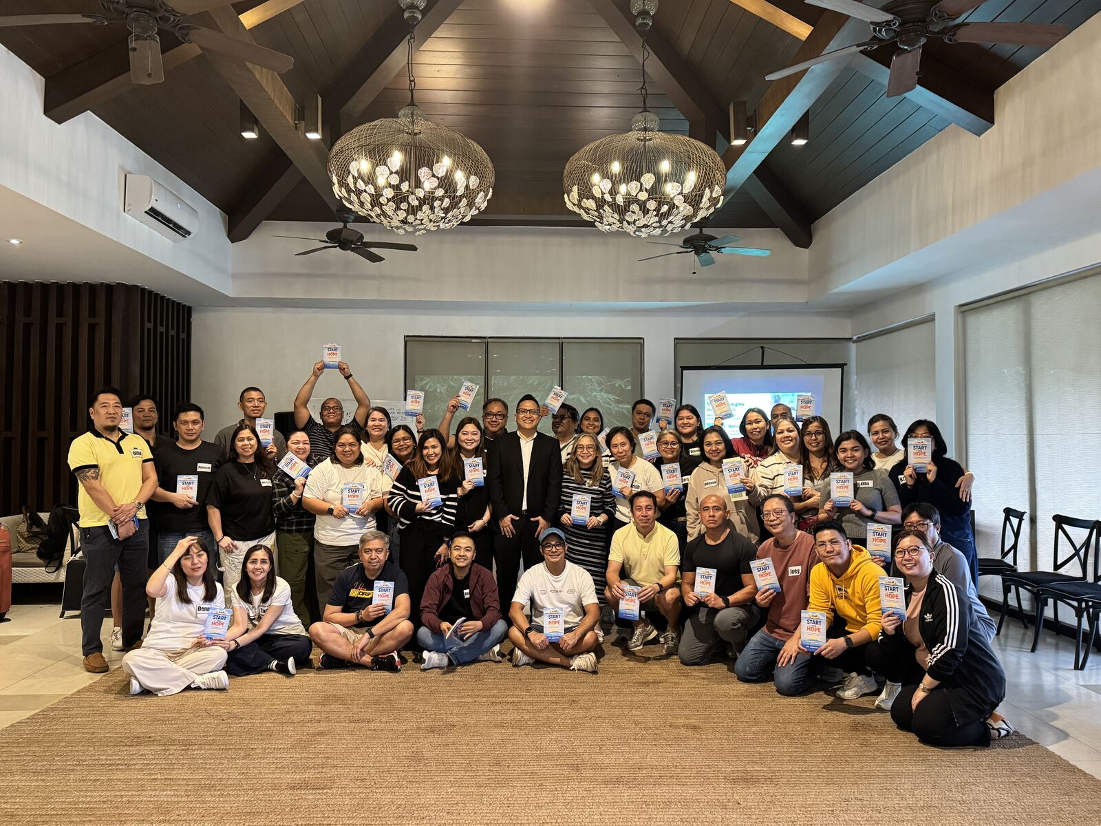 About forty Global Payments leaders with Jay Jaboneta, holding copies of Start with HOPE after the HOPE in Action session in Tagaytay